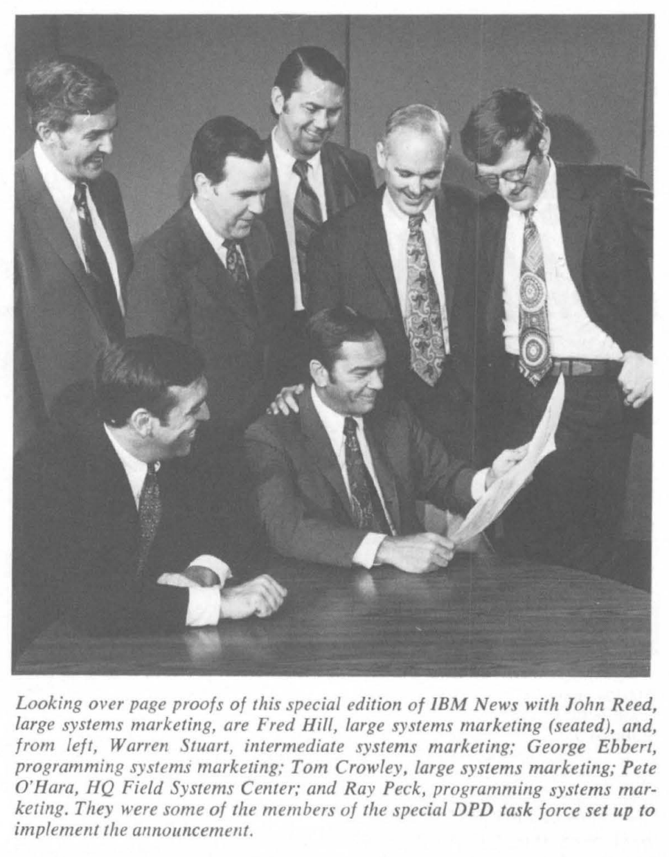 IBM staff in dark suits and ties reviewing page proofs of IBM News, 1972